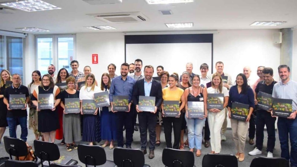Grupo de representantes municipais e profissionais de cultura e turismo posando em uma sala de eventos, cada um segurando o livro Circuito das Frutas – História, Cultura e Turismo, durante o lançamento oficial da obra.