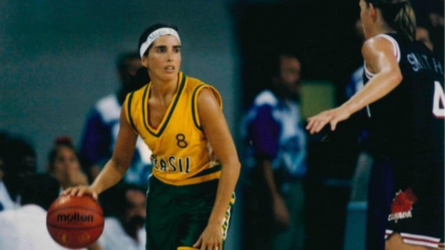 Jogadora da seleção brasileira de basquete dribla a bola durante partida, usando uniforme amarelo e verde em competição internacional.