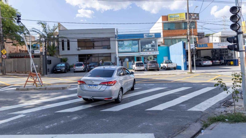 Cruzamento da Rua Catânia com a Rua Messina em Jundiaí, com nova sinalização, faixas de pedestres e semáforo, e um carro fazendo conversão. Cruzamento da Rua Catânia com a Rua Messina em Jundiaí, com nova sinalização, faixas de pedestres e semáforo, e um carro fazendo conversão.