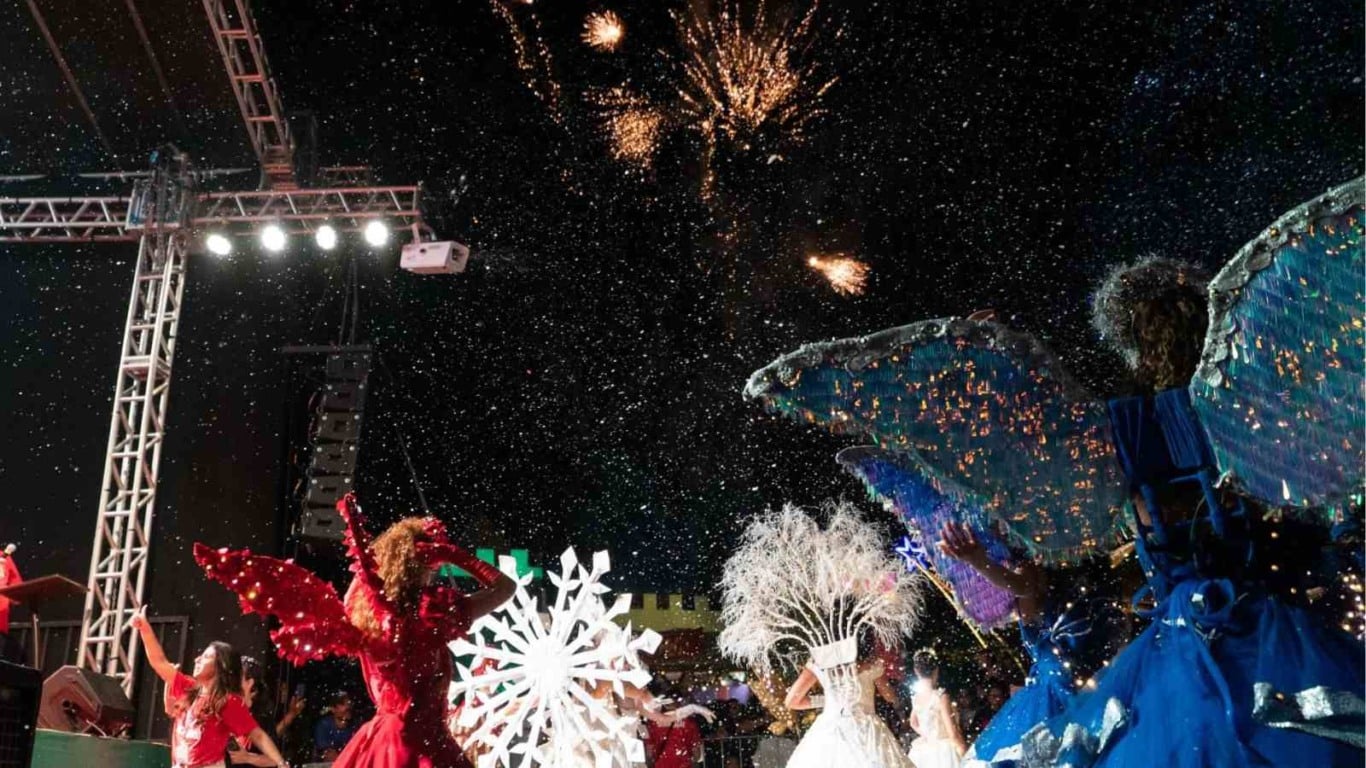 Dançarinos com fantasias coloridas de anjos se apresentam sob neve artificial enquanto fogos de artifício explodem no céu durante o Natal Encantado no Parque da Cidade. Dançarinos com fantasias coloridas de anjos se apresentam sob neve artificial enquanto fogos de artifício explodem no céu durante o Natal Encantado no Parque da Cidade.