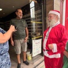 Papai Noel e Noelete conversam com comerciantes em frente a uma loja na Vila Hortolândia durante visita natalina da ACE.