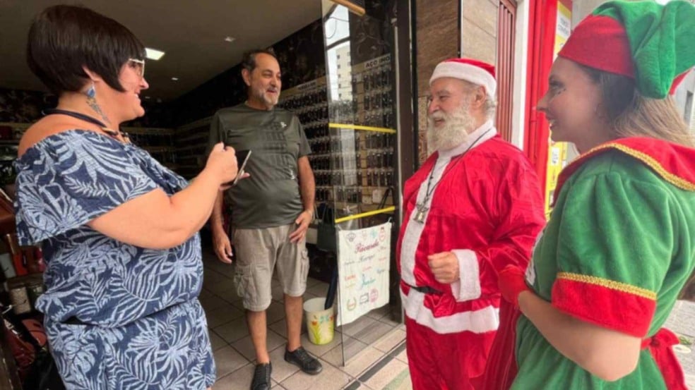 Papai Noel e Noelete conversam com comerciantes em frente a uma loja na Vila Hortolândia durante visita natalina da ACE. Papai Noel e Noelete conversam com comerciantes em frente a uma loja na Vila Hortolândia durante visita natalina da ACE.