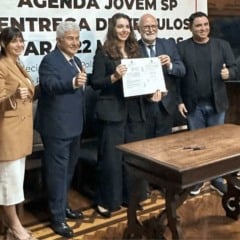 Autoridades posam com documento assinado durante evento da Agenda Jovem SP, marcando a entrega de apoio institucional &agrave;s pol&iacute;ticas p&uacute;blicas para a juventude.