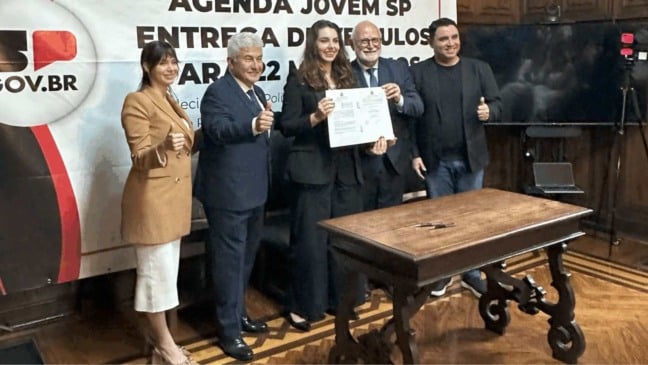 Autoridades posam com documento assinado durante evento da Agenda Jovem SP, marcando a entrega de apoio institucional às políticas públicas para a juventude.