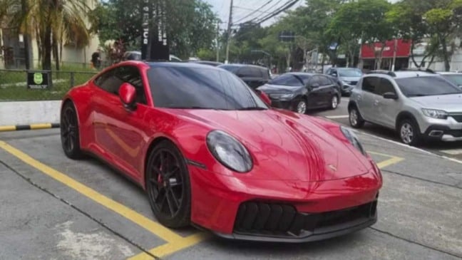 Porsche vermelho apreendido pela Polícia Civil estacionado em área do Deic, com outros veículos ao fundo.