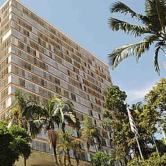 Pr&eacute;dio da Prefeitura de Campinas com fachada envidra&ccedil;ada, &aacute;rvores e palmeiras ao redor em dia ensolarado.