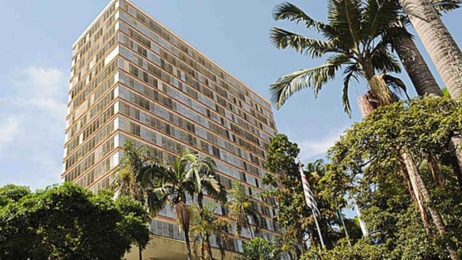 Prédio da Prefeitura de Campinas com fachada envidraçada, árvores e palmeiras ao redor em dia ensolarado.