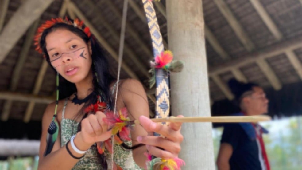 Criança indígena com pintura facial segura arco e flecha durante vivência cultural ao ar livre no Sesc Jundiaí. Criança indígena com pintura facial segura arco e flecha durante vivência cultural ao ar livre no Sesc Jundiaí.