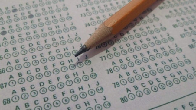 Cartão de respostas de prova objetiva com alternativas de múltipla escolha e lápis apontado sobre as questões, simbolizando a realização de um concurso público.