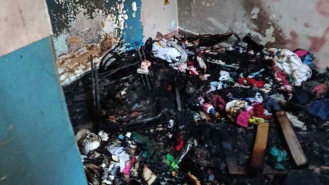 Interior de casa em Cabreúva após incêndio, com roupas e objetos queimados e paredes danificadas pelo fogo.