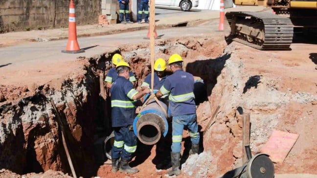 Trabalhadores da DAE Jundiaí instalam tubulação de saneamento em obra urbana.