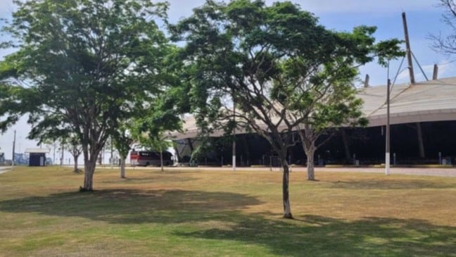 Área externa da Rodoviária de Jundiaí com gramado, árvores e o prédio do terminal ao fundo em dia ensolarado.