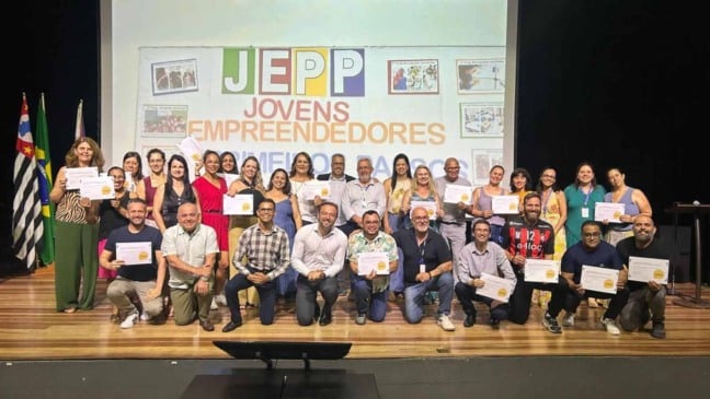 Grupo de professores, gestores e representantes da rede municipal de Itupeva posando no palco com certificados do Selo Escola Parceira 2025, diante de um telão com o logo do Jepp – Jovens Empreendedores Primeiros Passos.