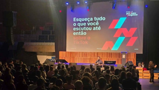 Palestrante fala a um auditório lotado no Sesc Jundiaí durante o evento “TikTok pro meu negócio”, com um telão exibindo a frase “Esqueça tudo o que você escutou até então sobre o TikTok”.