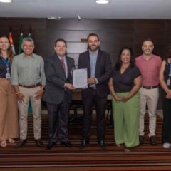 Grupo de autoridades de Jundiaí e do Detran-SP alinhados em pé para foto oficial; ao centro, o prefeito Gustavo Martinelli e Frederico Pierotti Arantes seguram o documento de adesão da cidade ao Sistran-SP.