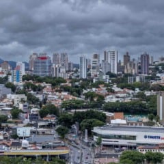 Cidade de Jundiaí vista de cima, com prédios e casas sob nuvens escuras e carregadas, indicando tempo instável e risco de ventos fortes.