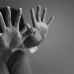 Pessoa com as m&atilde;os erguidas em sinal de defesa, representando vulnerabilidade e tentativa de prote&ccedil;&atilde;o diante de viol&ecirc;ncia.