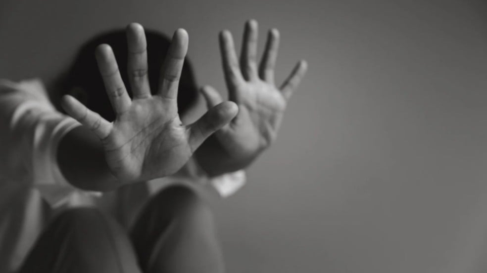 Pessoa com as mãos erguidas em sinal de defesa, representando vulnerabilidade e tentativa de proteção diante de violência. Pessoa com as mãos erguidas em sinal de defesa, representando vulnerabilidade e tentativa de proteção diante de violência.