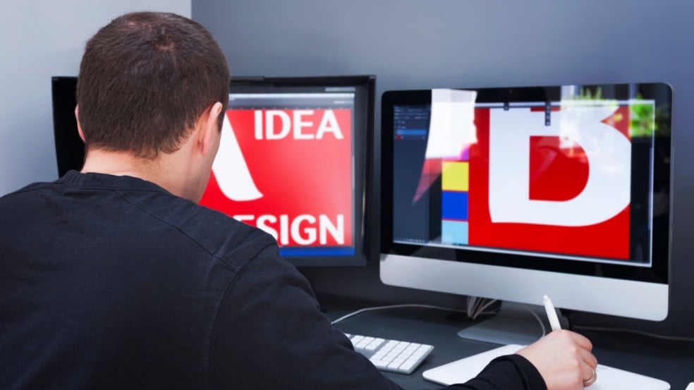 Homem usando caneta digital enquanto edita projetos de design gráfico em dois monitores, em um ambiente de trabalho moderno. Homem usando caneta digital enquanto edita projetos de design gráfico em dois monitores, em um ambiente de trabalho moderno.
