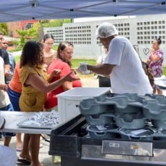 Servidores do Bom Prato M&oacute;vel distribuem marmitas a moradores em fila durante atendimento comunit&aacute;rio em bairro de V&aacute;rzea Paulista.