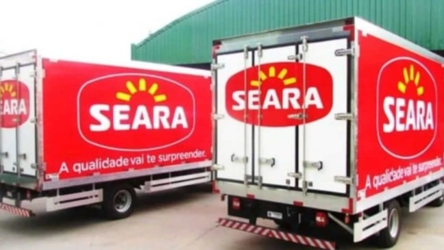 Caminhões da Seara com baús vermelhos e brancos, exibindo o logotipo da marca, estacionados em área industrial para transporte e distribuição de alimentos.