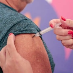 Profissional de saúde aplica vacina no braço de uma pessoa em ação de imunização durante evento público.