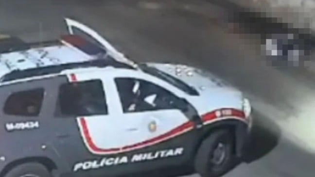 Viatura da Polícia Militar de São Paulo parada em avenida durante a madrugada, com porta aberta e motocicleta ao fundo, em cena registrada por câmera de segurança.