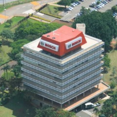 Vista aérea da unidade da Bosch em Campinas, com prédio corporativo envidraçado, logotipo da empresa no topo e estacionamento ao redor.