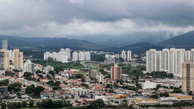 Vista de Jundiaí com prédios residenciais e a Serra do Japi ao fundo sob céu nublado e carregado, indicando tempo instável e possibilidade de chuva.