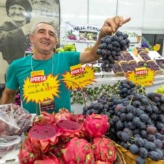 Produtor rural exibe cacho de uvas em estande com frutas variadas durante a Festa da Uva de Jundia&iacute;.