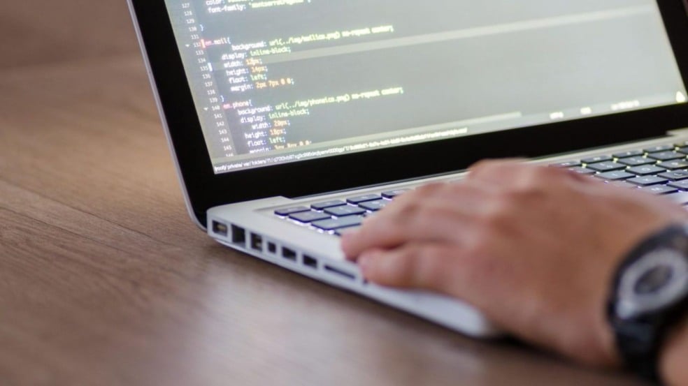 Pessoa digitando em notebook com código na tela, simbolizando cursos e qualificação profissional. Pessoa digitando em notebook com código na tela, simbolizando cursos e qualificação profissional.