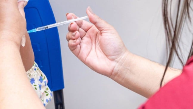 Profissional de saúde aplica vacina no braço de uma pessoa durante atendimento em unidade de saúde.