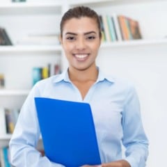Jovem mulher sorridente segura uma pasta azul em ambiente com estantes de livros, representando estudante ou estagi&aacute;ria em contexto educacional e profissional.