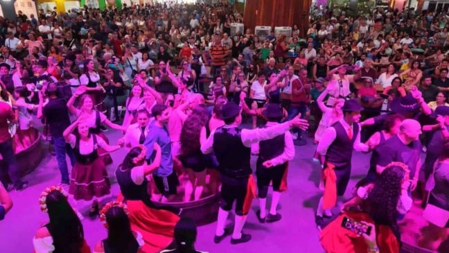 Público lota a Festa da Uva de Jundiaí durante dança e pisa da uva, com participantes em trajes típicos italianos e multidão acompanhando a apresentação cultural no Parque da Uva.