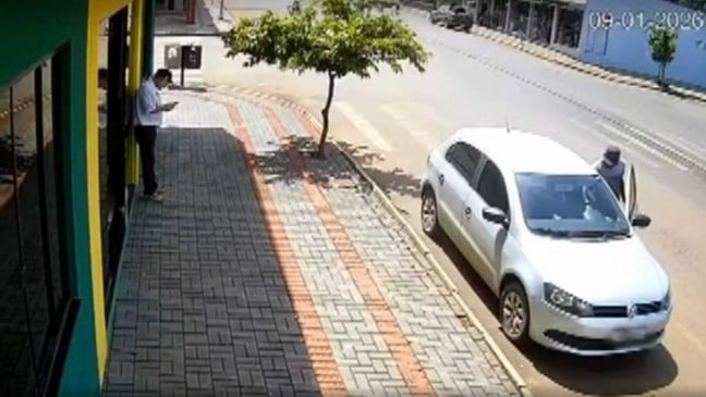 Câmera de segurança registra momento em que carro é levado por engano enquanto proprietário mexe no celular na calçada.