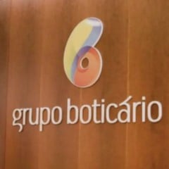Logotipo do Grupo Botic&aacute;rio aplicado em parede de madeira dentro de um ambiente corporativo.