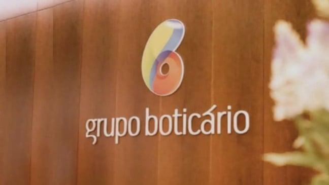 Logotipo do Grupo Boticário aplicado em parede de madeira dentro de um ambiente corporativo.