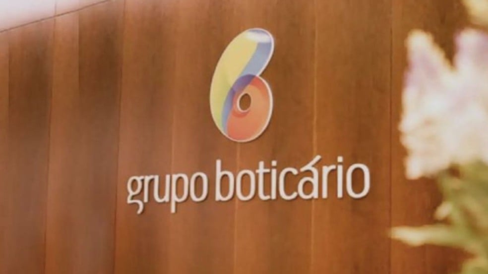 Logotipo do Grupo Boticário aplicado em parede de madeira dentro de um ambiente corporativo. Logotipo do Grupo Boticário aplicado em parede de madeira dentro de um ambiente corporativo.