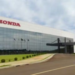 Fachada do pr&eacute;dio da Honda Brasil com arquitetura moderna, fachada de vidro, logotipo da marca em destaque e bandeiras hasteadas na entrada.