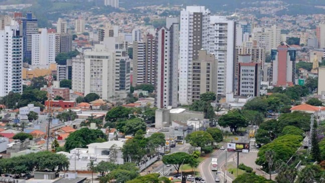 Vista aérea de Jundiaí com prédios altos, ruas arborizadas e áreas verdes em meio à malha urbana da cidade.