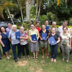 Moradores do bairro Pracatu, em Jundia&iacute;, posam em &aacute;rea verde segurando pastas azuis com matr&iacute;culas de im&oacute;veis entregues pela Prefeitura.