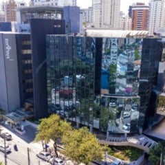 Vista a&eacute;rea de hospital da Rede D&rsquo;Or em S&atilde;o Paulo, com fachada de vidro espelhado, pr&eacute;dios ao redor e ruas movimentadas.