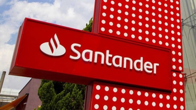 Fachada de agência do banco Santander com logotipo branco em painel vermelho.