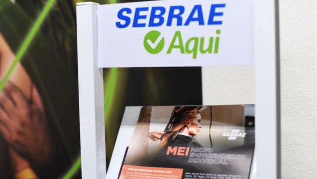 Placa do Sebrae Aqui com material informativo sobre MEI em ponto de atendimento ao microempreendedor.