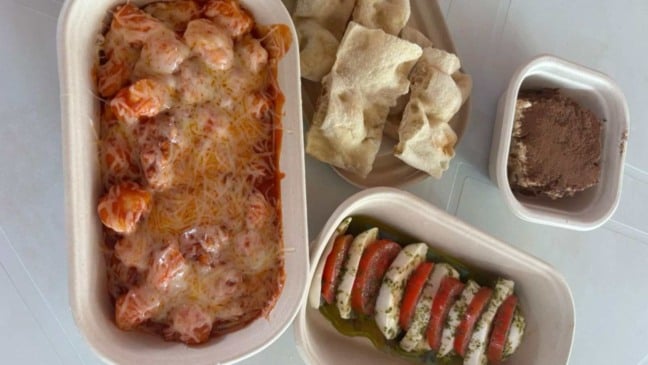 Pratos italianos do estande da Teia Down na Festa da Uva de Jundiaí, com gnocchi ao molho, salada caprese, pão e tiramisù.