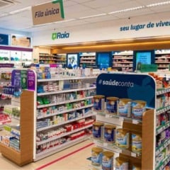 Interior de uma farm&aacute;cia Raia com prateleiras de medicamentos e produtos de sa&uacute;de, ambiente amplo, iluminado e organizado para atendimento ao p&uacute;blico.