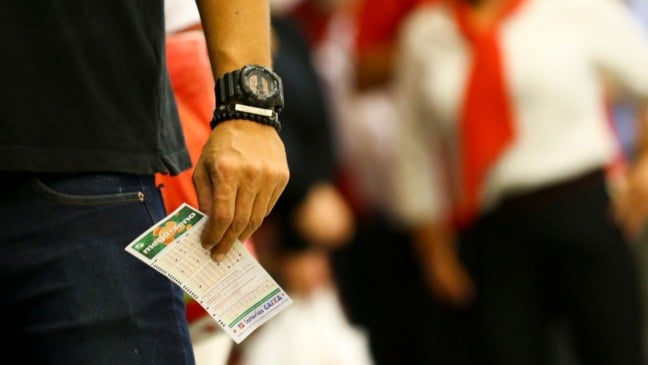 Homem segurando um bilhete da Mega-Sena