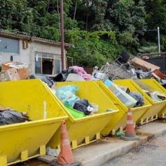 Ca&ccedil;ambas amarelas cheias de m&oacute;veis, eletrodom&eacute;sticos e res&iacute;duos inserv&iacute;veis em &aacute;rea p&uacute;blica de descarte em V&aacute;rzea Paulista.