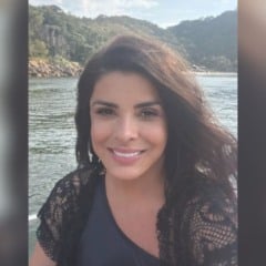 Mara Maravilha sorri para a c&acirc;mera em foto ao ar livre, com rio e morros cobertos por vegeta&ccedil;&atilde;o ao fundo.