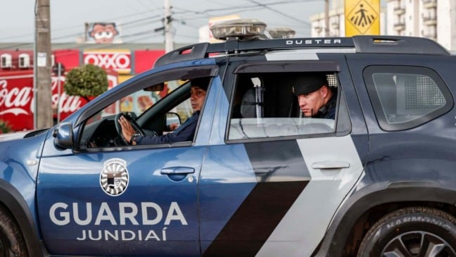 Viatura da Guarda Municipal de Jundiaí com dois agentes uniformizados durante patrulhamento em rua da cidade.